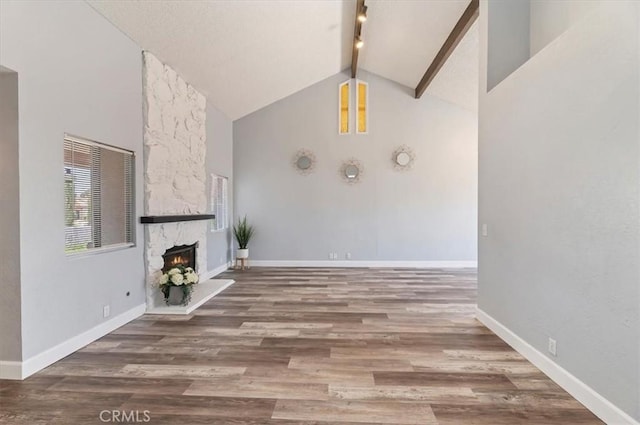 3920 Roxbury Dr, Hemet, CA 92545 - unfurnished living room featuring high vaulted ceiling, beam ceiling, a stone fireplace, and wood finished floors