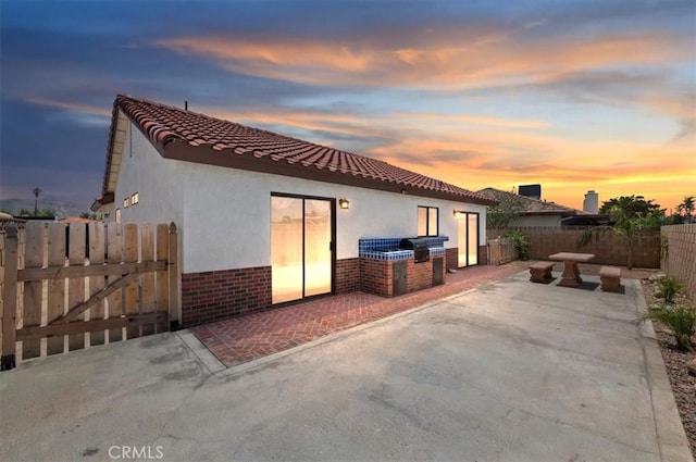 3920 Roxbury Dr, Hemet, CA 92545 - back of property at dusk with a fenced backyard, a patio, stucco siding, and brick siding