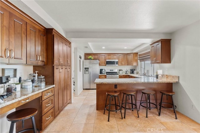 20241 Edmund Rd, Riverside, CA 92508 - kitchen featuring appliances with stainless steel finishes, light stone countertops, a peninsula, and brown cabinetry