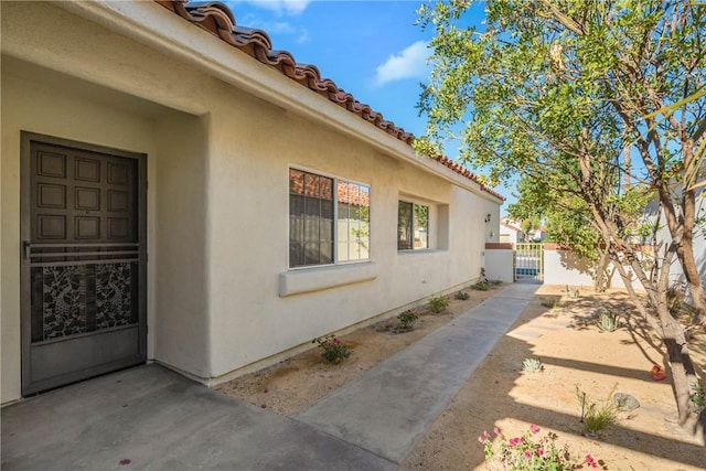 43791 Calle Las Brisas W, Palm Desert, CA 92211 - view of side of home featuring a gate, stucco siding, and a tiled roof