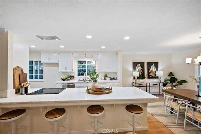 6330 N Wilson Ave, Fresno, CA 93704 - kitchen featuring black electric stovetop, white cabinetry, a breakfast bar area, a peninsula, and stainless steel dishwasher