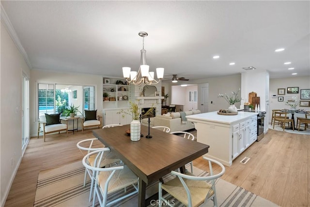 6330 N Wilson Ave, Fresno, CA 93704 - dining space with a fireplace, a chandelier, light wood-type flooring, recessed lighting, and crown molding