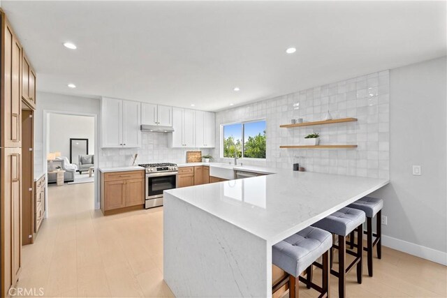 9211 Regency Way, Rancho Cucamonga, CA 91701 - kitchen featuring gas stove, a peninsula, backsplash, under cabinet range hood, and a breakfast bar area