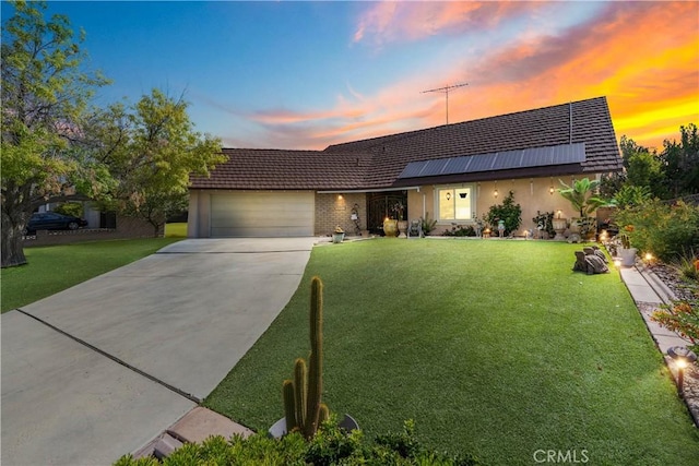43657 21st St W, Lancaster, CA 93536 - view of front of house featuring an attached garage, solar panels, a front lawn, driveway, and stucco siding
