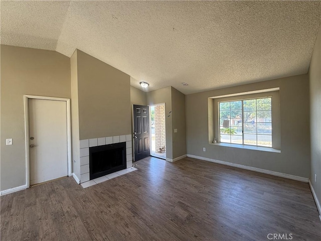 15569 Athol St, Fontana, CA 92335 - unfurnished living room with wood finished floors, a tiled fireplace, a textured ceiling, and vaulted ceiling
