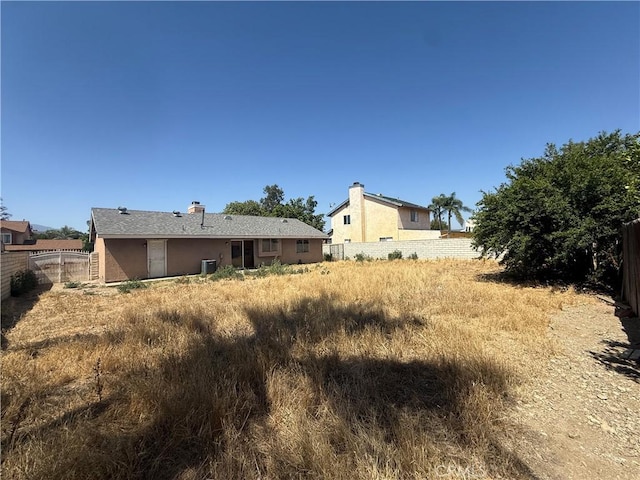 15569 Athol St, Fontana, CA 92335 - back of property featuring a fenced backyard, stucco siding, and a chimney