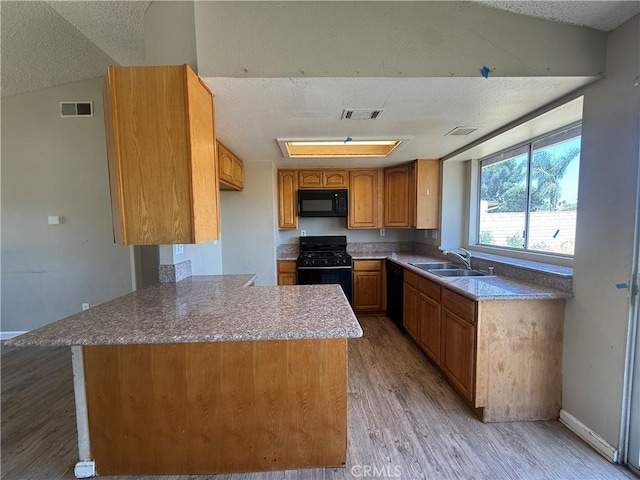 15569 Athol St, Fontana, CA 92335 - kitchen with black appliances, light wood-type flooring, a peninsula, brown cabinets, and a textured ceiling