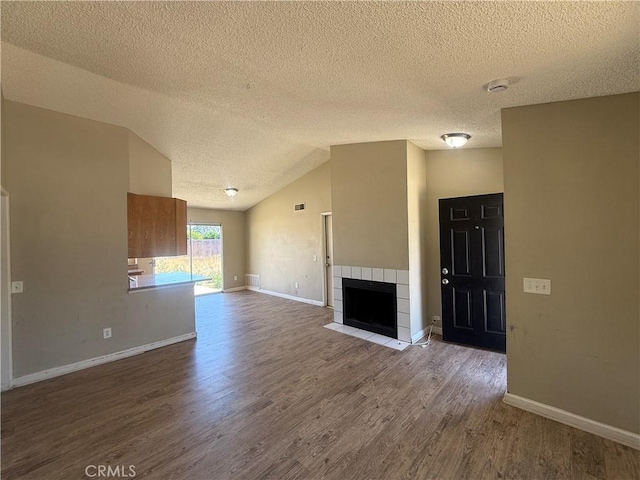 15569 Athol St, Fontana, CA 92335 - unfurnished living room with wood finished floors, a textured ceiling, a fireplace, and vaulted ceiling