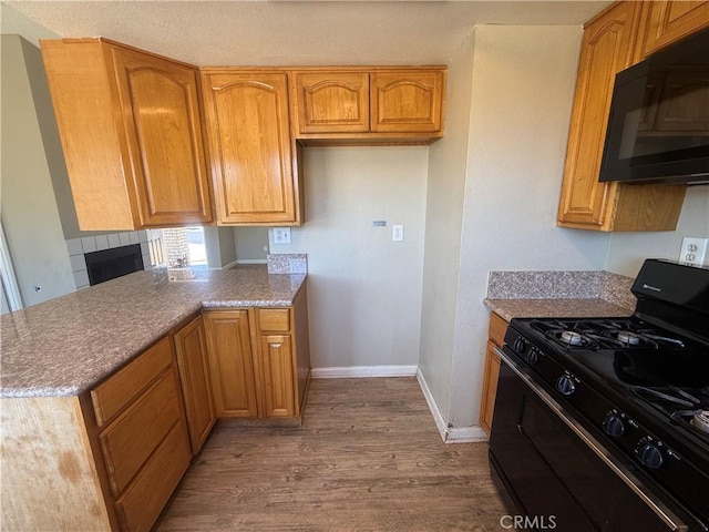 15569 Athol St, Fontana, CA 92335 - kitchen featuring black appliances, wood finished floors, a peninsula, and brown cabinets