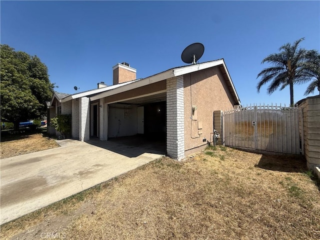 15569 Athol St, Fontana, CA 92335 - view of side of home featuring a gate, driveway, and a chimney