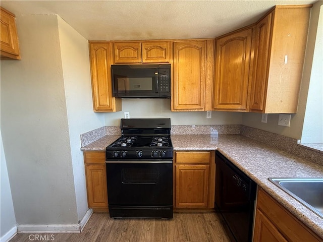 15569 Athol St, Fontana, CA 92335 - kitchen featuring black appliances, light wood-style flooring, brown cabinets, and light countertops