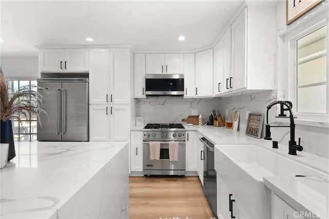 10171 Kukui Dr, Huntington Beach, CA 92646 - kitchen with high quality appliances, white cabinetry, tasteful backsplash, recessed lighting, and light stone counters
