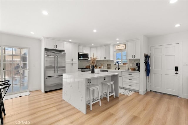 10171 Kukui Dr, Huntington Beach, CA 92646 - kitchen with stainless steel appliances, a kitchen island, white cabinetry, light wood finished floors, and recessed lighting