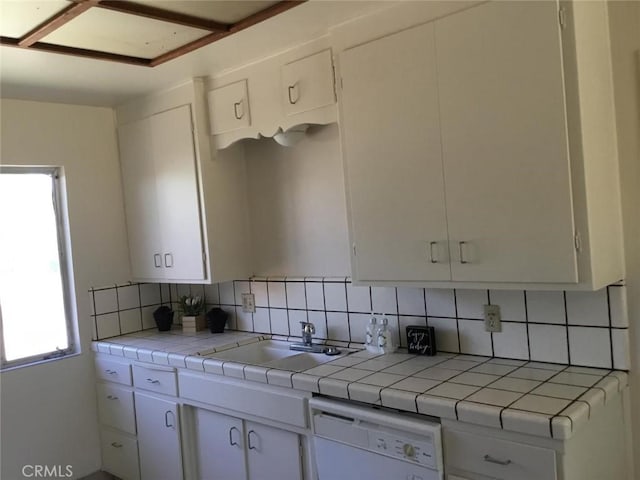 2911 Tahoe Dr, Merced, CA 95340 - kitchen with white dishwasher, tile countertops, white cabinets, and backsplash
