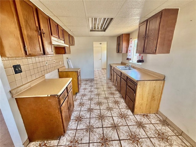 2516 Tamora Ave, South El Monte, CA 91733 - kitchen featuring under cabinet range hood, a paneled ceiling, light countertops, brown cabinets, and light tile patterned flooring