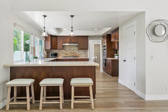 245 S Via Montanera, Anaheim Hills, CA 92807 - kitchen featuring a tray ceiling, a peninsula, light countertops, light wood finished floors, and recessed lighting
