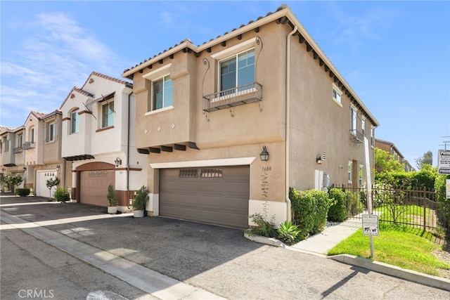 7600 N Courage Way, Van Nuys, CA 91405 - view of property featuring an attached garage, stucco siding, asphalt driveway, and a residential view