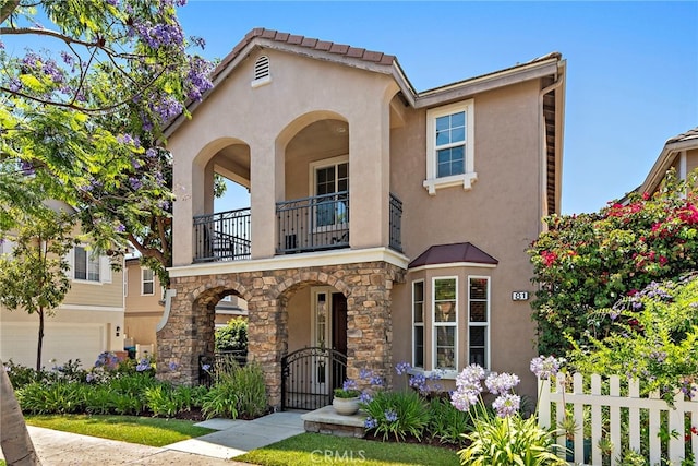 81 Mercantile Way, Ladera Ranch, CA 92694 - mediterranean / spanish-style house with a balcony, stucco siding, stone siding, and an attached garage