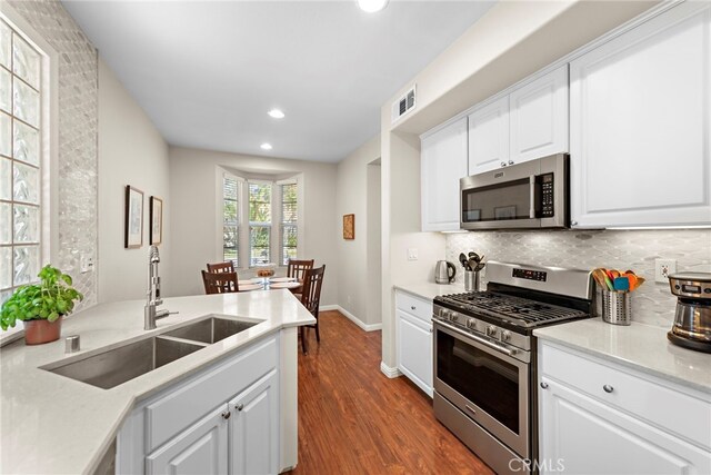81 Mercantile Way, Ladera Ranch, CA 92694 - kitchen with stainless steel appliances, dark wood-type flooring, recessed lighting, decorative backsplash, and white cabinets