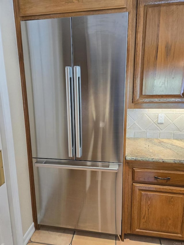 4970 Beauchamp Ct, San Diego, CA 92130 - kitchen featuring high quality fridge, brown cabinets, light stone counters, light tile patterned floors, and backsplash