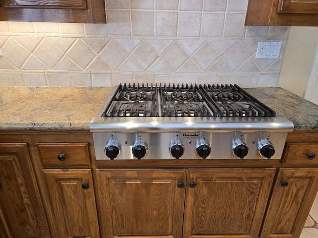 4970 Beauchamp Ct, San Diego, CA 92130 - kitchen view of stainless steel gas cooktop, backsplash, brown cabinets, and light stone counters