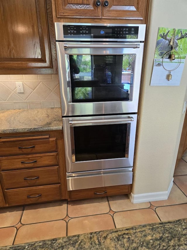 4970 Beauchamp Ct, San Diego, CA 92130 - kitchen with stainless steel double oven, tile patterned flooring, tasteful backsplash, and brown cabinetry