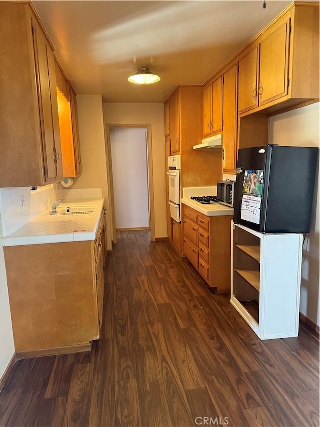 7395 Sage Ave, Yucca Valley, CA 92284 - kitchen with under cabinet range hood, dark wood finished floors, oven, a warming drawer, and gas stovetop