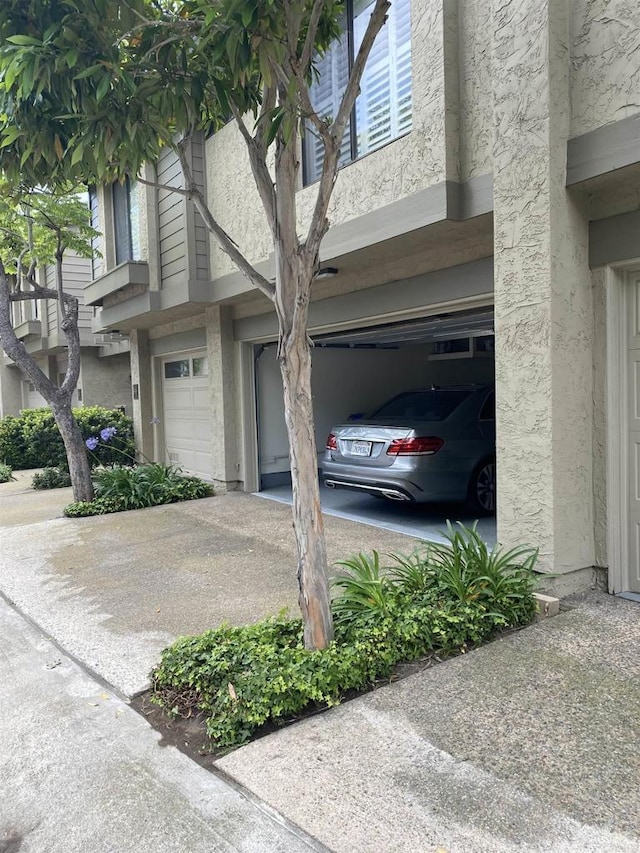 5983 Gaines St, San Diego, CA 92110 - view of home's exterior with an attached garage, stucco siding, and driveway
