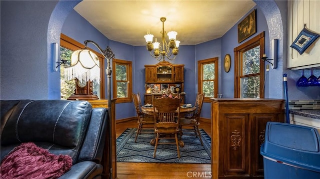 24083 Cresta Dr, Crestline, CA 92325 - dining space with a chandelier, arched walkways, and wood finished floors