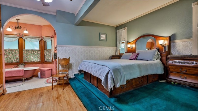 24083 Cresta Dr, Crestline, CA 92325 - bedroom with wainscoting, wood finished floors, wallpapered walls, arched walkways, and ornamental molding
