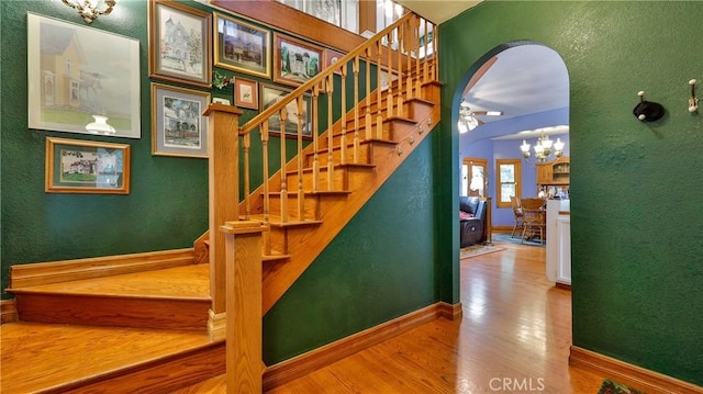 24083 Cresta Dr, Crestline, CA 92325 - staircase with wood finished floors, a chandelier, and arched walkways