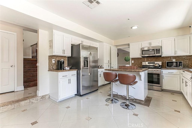15521 Sandra Ln, Sylmar, CA 91342 - kitchen featuring appliances with stainless steel finishes, a breakfast bar area, decorative backsplash, white cabinets, and recessed lighting