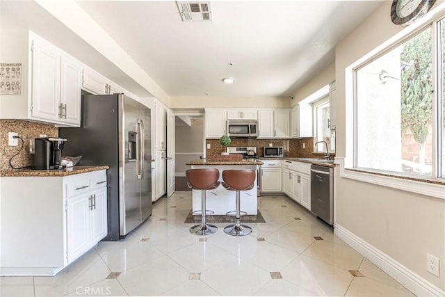 15521 Sandra Ln, Sylmar, CA 91342 - kitchen featuring stainless steel appliances, white cabinets, plenty of natural light, and tasteful backsplash