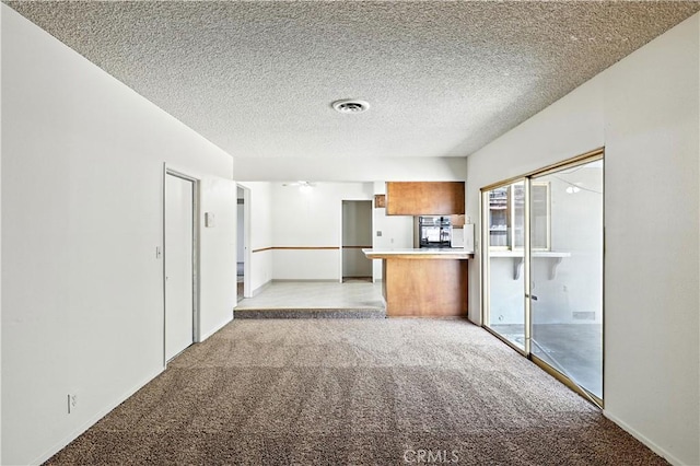 457 Brian Ct, Merced, CA 95348 - kitchen with a peninsula, light colored carpet, stainless steel oven, brown cabinetry, and a textured ceiling