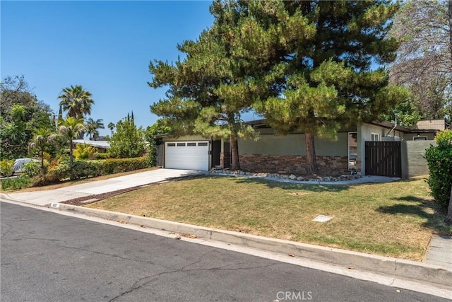 14137 Viburnum Dr, Whittier, CA 90604 - view of property hidden behind natural elements with driveway, a front lawn, stone siding, an attached garage, and a gate