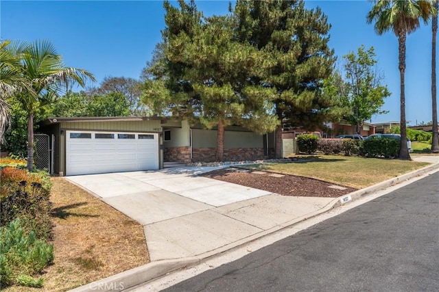 14137 Viburnum Dr, Whittier, CA 90604 - view of front facade featuring stone siding, a garage, concrete driveway, and a front yard
