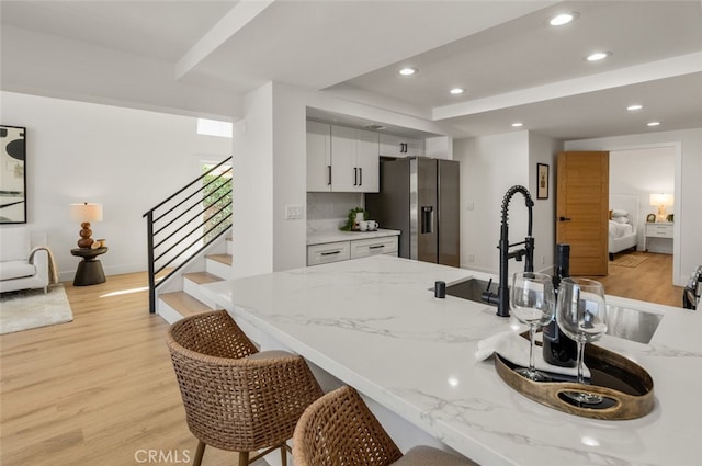 22627 Lakeside Ln, Lake Forest, CA 92630 - kitchen with stainless steel fridge with ice dispenser, light wood-style flooring, a breakfast bar, white cabinets, and recessed lighting