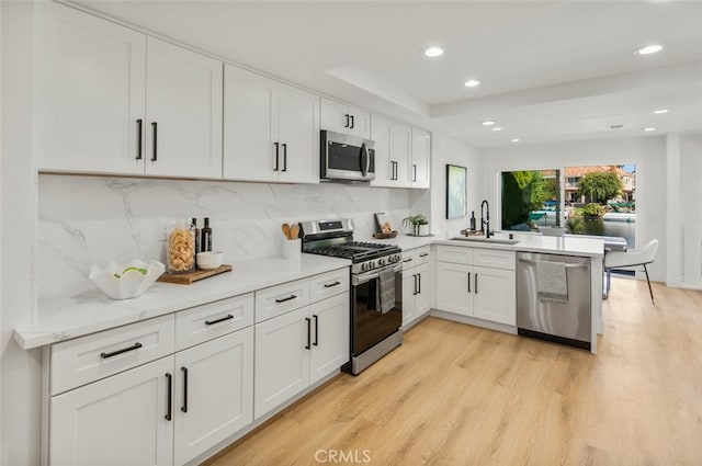 22627 Lakeside Ln, Lake Forest, CA 92630 - kitchen featuring appliances with stainless steel finishes, a peninsula, white cabinets, light wood-style floors, and backsplash