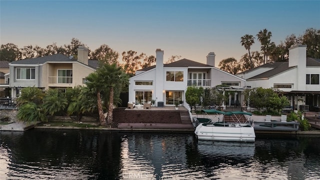 22627 Lakeside Ln, Lake Forest, CA 92630 - back of house at dusk featuring a water view, a patio, and stucco siding