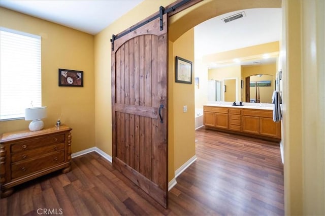 42365 Westar Ct, Murrieta, CA 92562 - corridor featuring arched walkways, a barn door, and dark wood-style floors