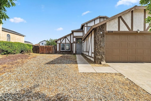 2134 Moonlight Ct, Palmdale, CA 93550 - tudor home featuring stucco siding, a garage, driveway, and stone siding