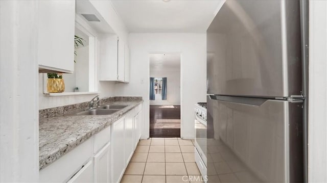 533 E Fredricks St, Barstow, CA 92311 - kitchen featuring freestanding refrigerator, white cabinetry, light tile patterned floors, light countertops, and white stove