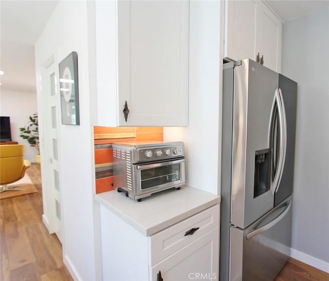 170 Avenida Majorca Unit A, Laguna Woods, CA 92637 - kitchen with stainless steel refrigerator with ice dispenser, white cabinetry, light wood finished floors, and light countertops