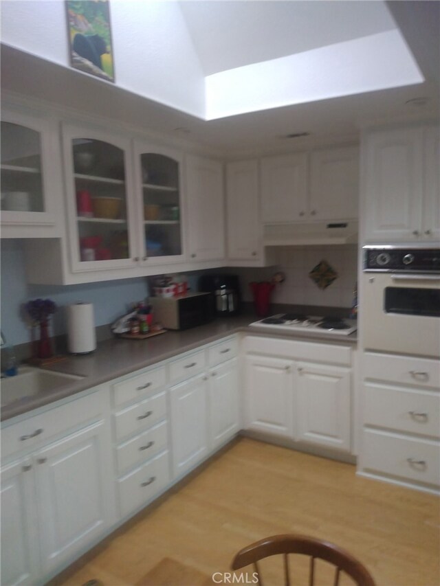 13141 Shawnee Ln Unit M-11 # 267-C, Seal Beach, CA 90740 - kitchen featuring white appliances, under cabinet range hood, white cabinetry, and glass insert cabinets