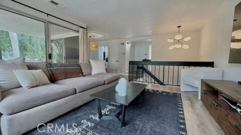 22215 Caminito Vino, Laguna Hills, CA 92653 - living area featuring healthy amount of natural light, a chandelier, and wood finished floors