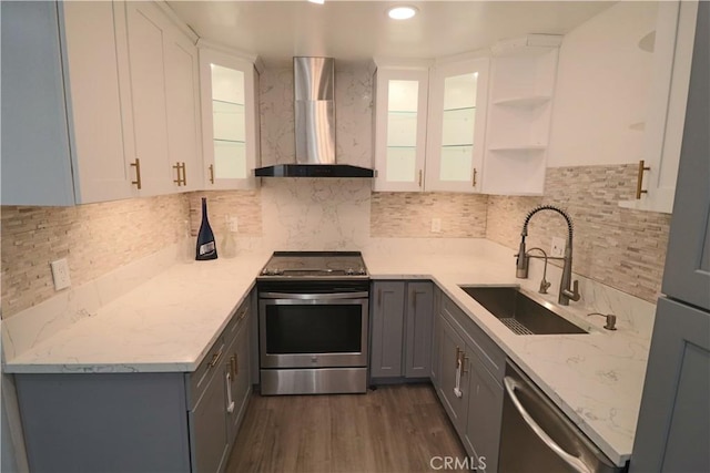 1602 N King St Unit E1, Santa Ana, CA 92706 - kitchen with wall chimney range hood, stainless steel appliances, gray cabinetry, open shelves, and backsplash