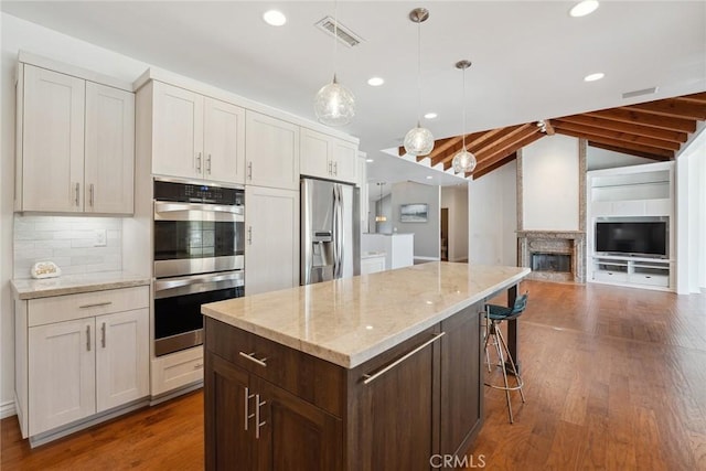 22501 Marilla St, Chatsworth, CA 91311 - kitchen with stainless steel appliances, lofted ceiling, dark wood-style flooring, white cabinetry, and a center island