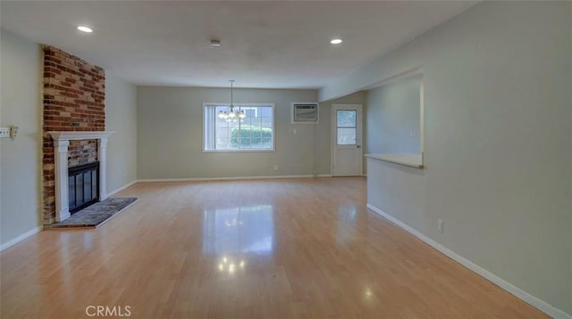 12911 Browning Ave, North Tustin, CA 92705 - unfurnished living room with a wall mounted AC, a chandelier, light wood-style floors, a brick fireplace, and recessed lighting