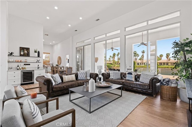56610 Muirfield Ln, Quinta, CA 92253 - living area with beverage cooler, light wood-style floors, a dry bar, recessed lighting, and a towering ceiling
