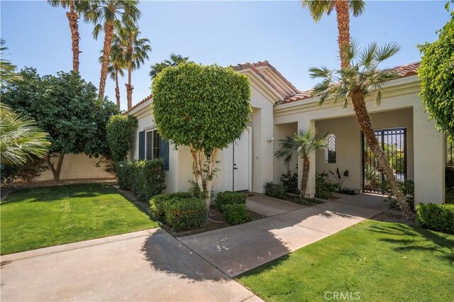 56610 Muirfield Ln, Quinta, CA 92253 - obstructed view of property with stucco siding, a front yard, and a tile roof